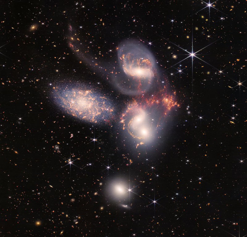 Figuur 10: De vijf sterrenstelsels van het Stephan’s Quintet. Dit is een gecombineerd beeld gemaakt met de NIRCam en MIRI meetinstrumenten en bestaat uit een mozaïek van 1000 afzonderlijke beelden. Het geeft inzicht in de evolutie van sterrenstelsels. Bron: NASA, ESA, CSA, and STScl.